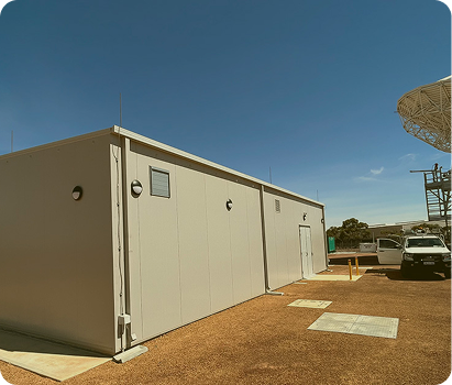 A satellite dish located behind a building, representing the role of critical power systems in Inmarsat Equipment Room