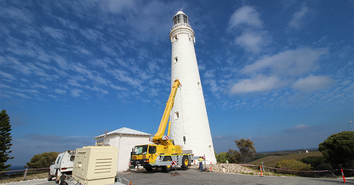 HIAB crane truck beside Rottnest Island Lighthouse supporting backup power systems installation and electrical infrastructure work.