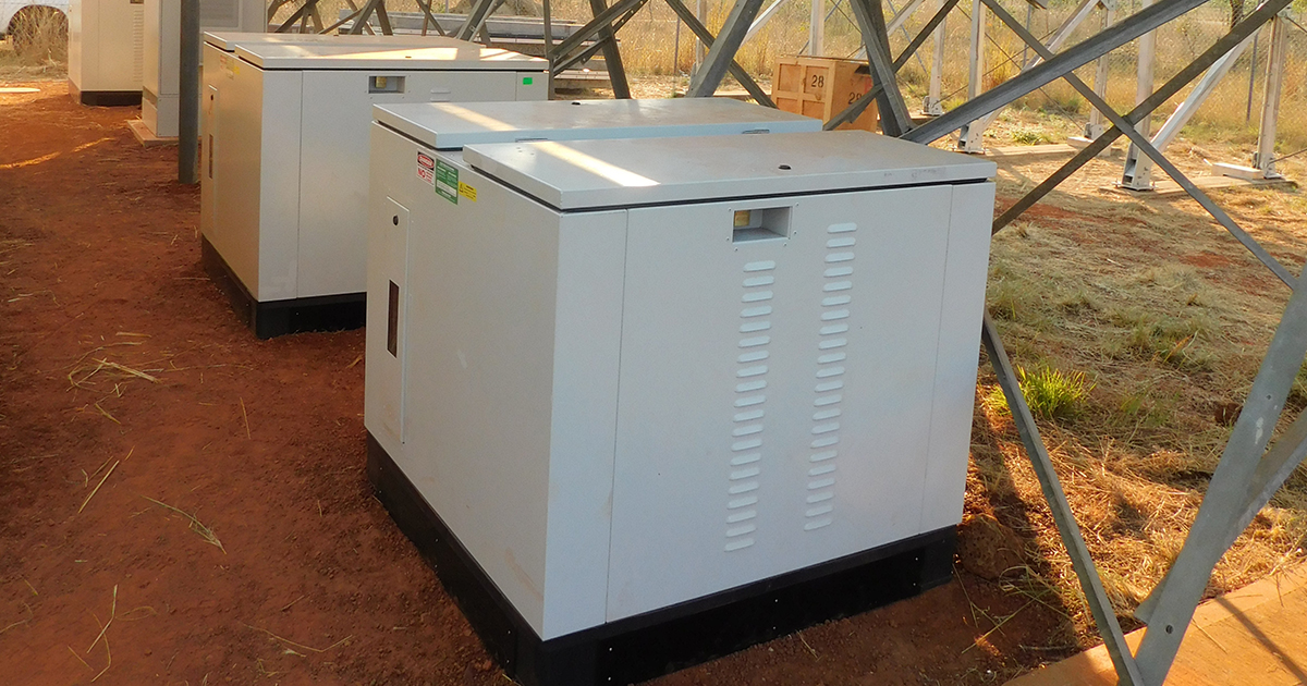White electrical boxes installed on a dirt site as part of a solar battery hybrid system across SA, WA and NT.