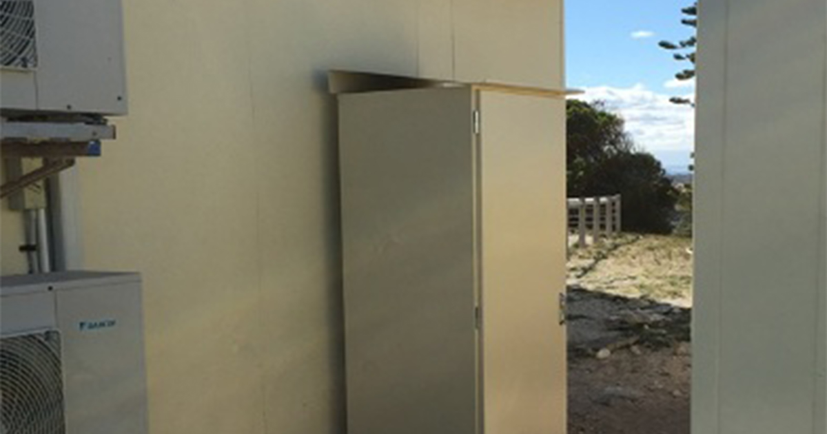 White electrical cabinet beside an aircon unit supporting backup power systems installation at Rottnest Island.